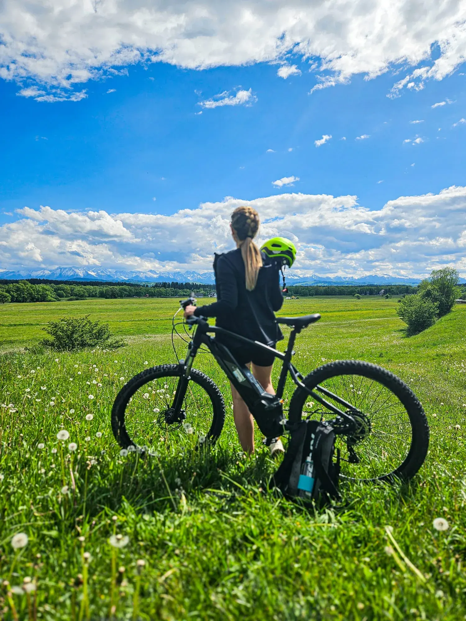 Rowerzystka podziwia panoramę Tatr z polnej łąki